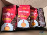 trois paquets de café sont posés dans une boîte en carton sur une table