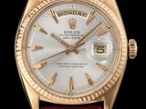 une montre Rolex en or avec un cadran blanc et un bracelet en cuir marron