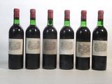 six bottles of wine are lined up on a white surface