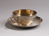 une tasse et une soucoupe en argent posées sur une soucoupe