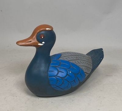 un canard bleu et marron posé sur une surface blanche