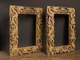 pair of antique carved wood picture frames on a wooden table