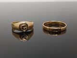 two gold rings on a black surface with a white background