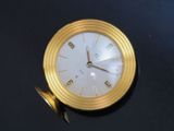 a gold clock sitting on a black table with a black background