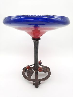 un bol en verre bleu et rouge posé sur un socle en métal
