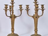 pair of antique brass candelabs on pedestals against a white background