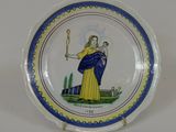une assiette bleue et jaune sur laquelle est représentée une femme tenant un bébé dans ses bras