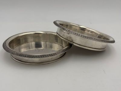 a pair of silver plated bowls on a white surface