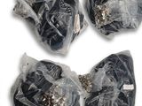 quatre morceaux de plastique noir emballés dans des sacs en plastique, posés sur une surface blanche