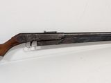 un vieux fusil de chasse avec une crosse en bois posé sur une surface blanche