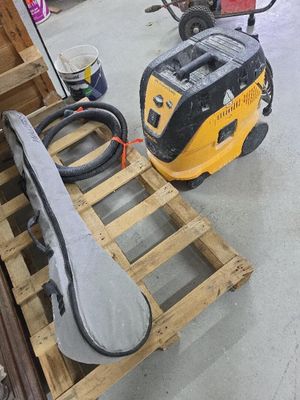 un aspirateur jaune et noir posé sur une palette dans un garage