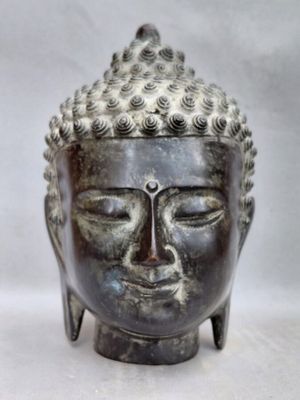 statue représentant une tête de Bouddha aux yeux fermés sur fond blanc