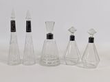 quatre bouteilles en verre transparent avec des bouchons noirs et un bouchon noir