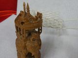a small wooden object on a table next to a thread spool