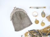 a silver purse and other jewelry on a white surface
