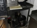 pots and pans are stacked on a metal shelf in a kitchen