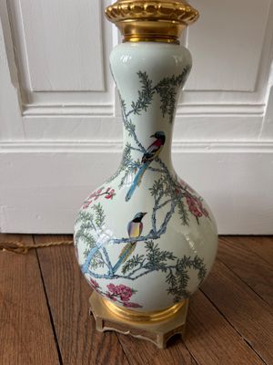 un vase blanc orné d'oiseaux, posé sur un plancher en bois