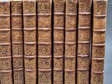 several old books are lined up in a row on a gray surface