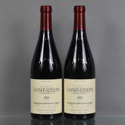 two bottles of wine sit on a glass table in front of a gray wall