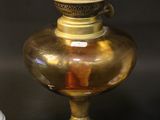 an antique brass oil lamp with a clear glass shade on top of it