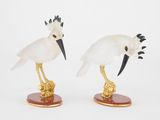 deux figurines d'oiseaux aux plumes noires et blanches, posées sur des socles en bois