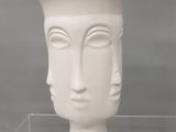 un vase blanc orné d'un visage, exposé dans une vitrine