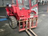 a red forklift parked in a warehouse with other equipment