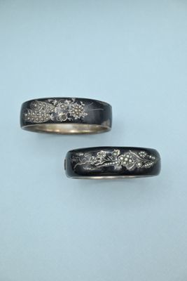 pair of black and gold wedding bands with flowers and leaves
