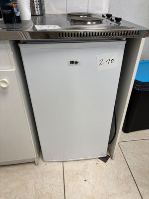 a small white dishwasher sitting in the corner of a kitchen