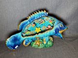 une figurine de poisson bleue posée sur un socle vert