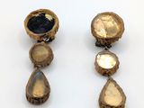 deux paires de boucles d'oreilles en or et en pierres noires posées sur un fond blanc