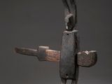 une sculpture en bois représentant une personne tenant un couteau, posée sur une table