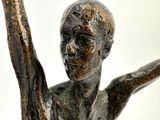 a bronze statue of a man holding a tennis racket