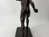 bronze statue of a man holding a ball on a black base