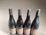 four bottles of wine are lined up on a white surface