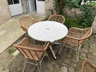une table blanche et quatre chaises disposées sur une terrasse en pierre