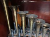 a bunch of silver trumpets sitting on a wooden shelf