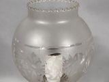 a glass vase with a white flower in it on a gold stand