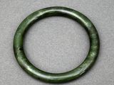 un gros plan d'un bracelet vert posé sur une surface grise
