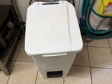 a white trash can sitting next to a sink in a bathroom