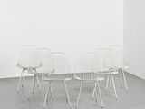 quatre chaises en fil de fer blanches dans une pièce blanche aux murs blancs