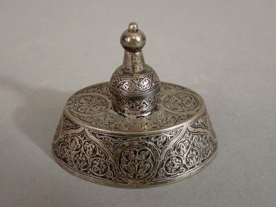 a small silver bell with a decorative design on it