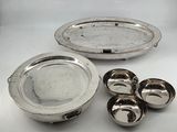 a silver plate with four bowls and four spoons next to it