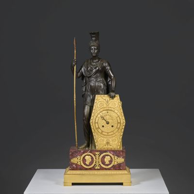 statue d'un homme tenant un bâton et une horloge, posée sur un socle