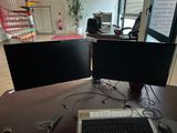 two computer monitors sitting on a desk with a keyboard and mouse
