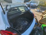 a white car with its trunk open on the side of the road