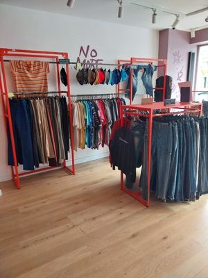 un portemanteau dans un magasin de vêtements, sur lequel sont suspendus des vêtements