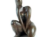 statue of a woman sitting on her knees on a white surface