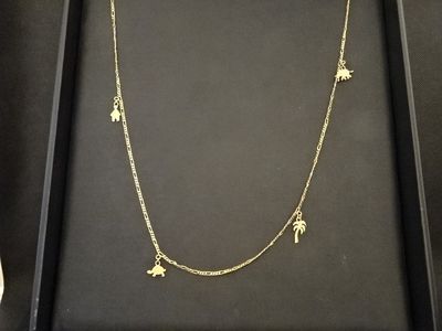 une boîte noire sur laquelle sont accrochés un collier en or et deux breloques