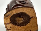 a wooden sculpture of a man ' s head on a white surface